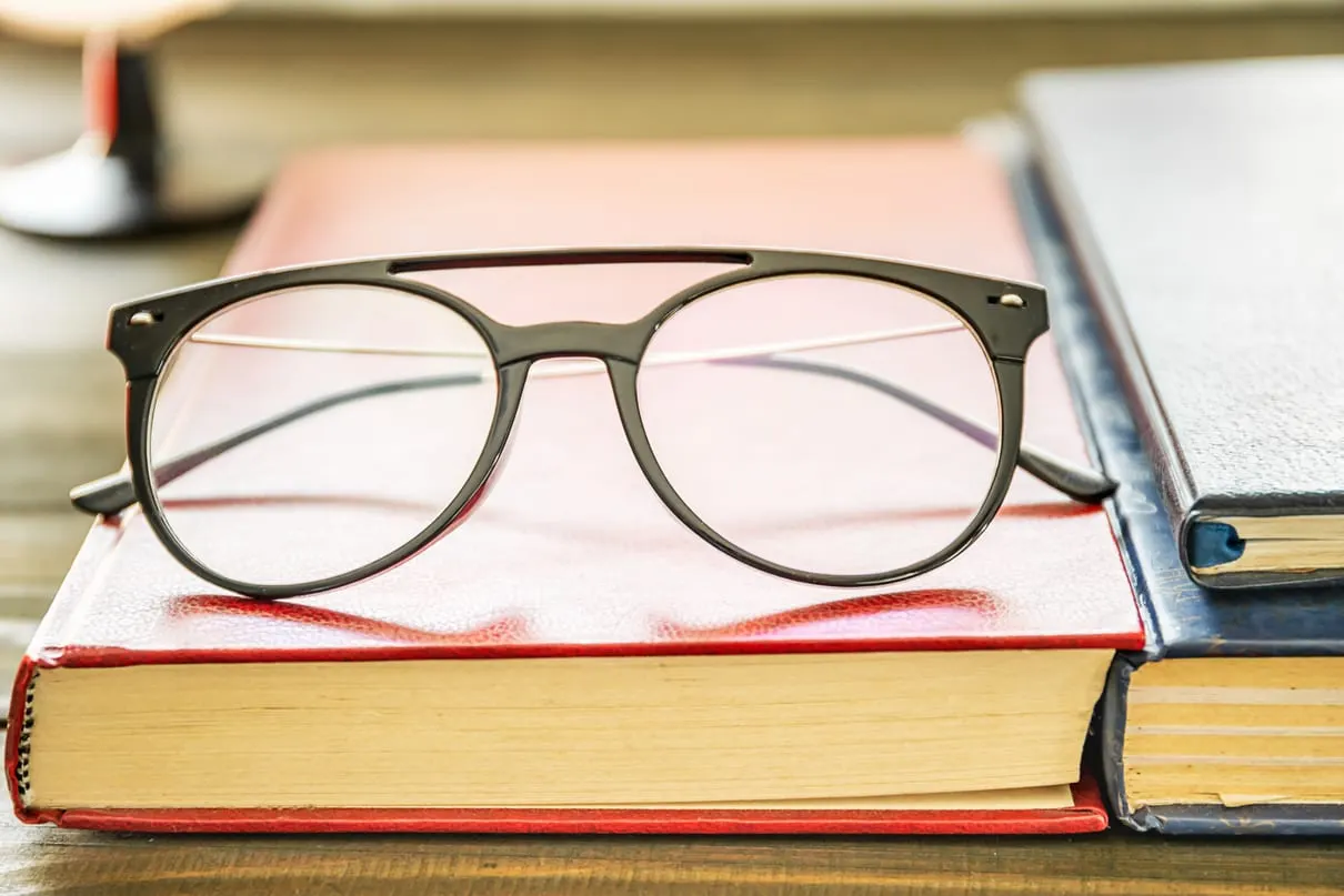 A pair of glasses resting on a stack of books